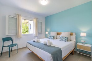 A bedroom with a bed, a chair, a nightstand, and a window with curtains. - Son Bou Playa Gold (Alayor)