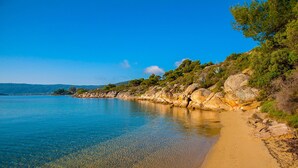 A beach with clear water, rocky shoreline, and greenery. - Thalassokipos (Sithonia)