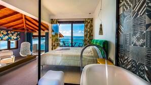A hotel room with a bed, a bathroom, a seating area with a view of the sea, and a balcony with a table and chairs. - Thalassokipos (Sithonia)