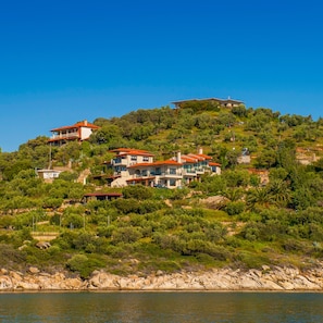 A hillside property with multiple buildings, including a large house with a red roof and several smaller structures. - Thalassokipos (Sithonia)