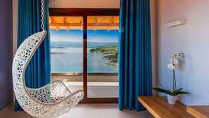 A room with a hanging chair, a view of a coastal landscape, and a potted orchid. - Thalassokipos (Sithonia)
