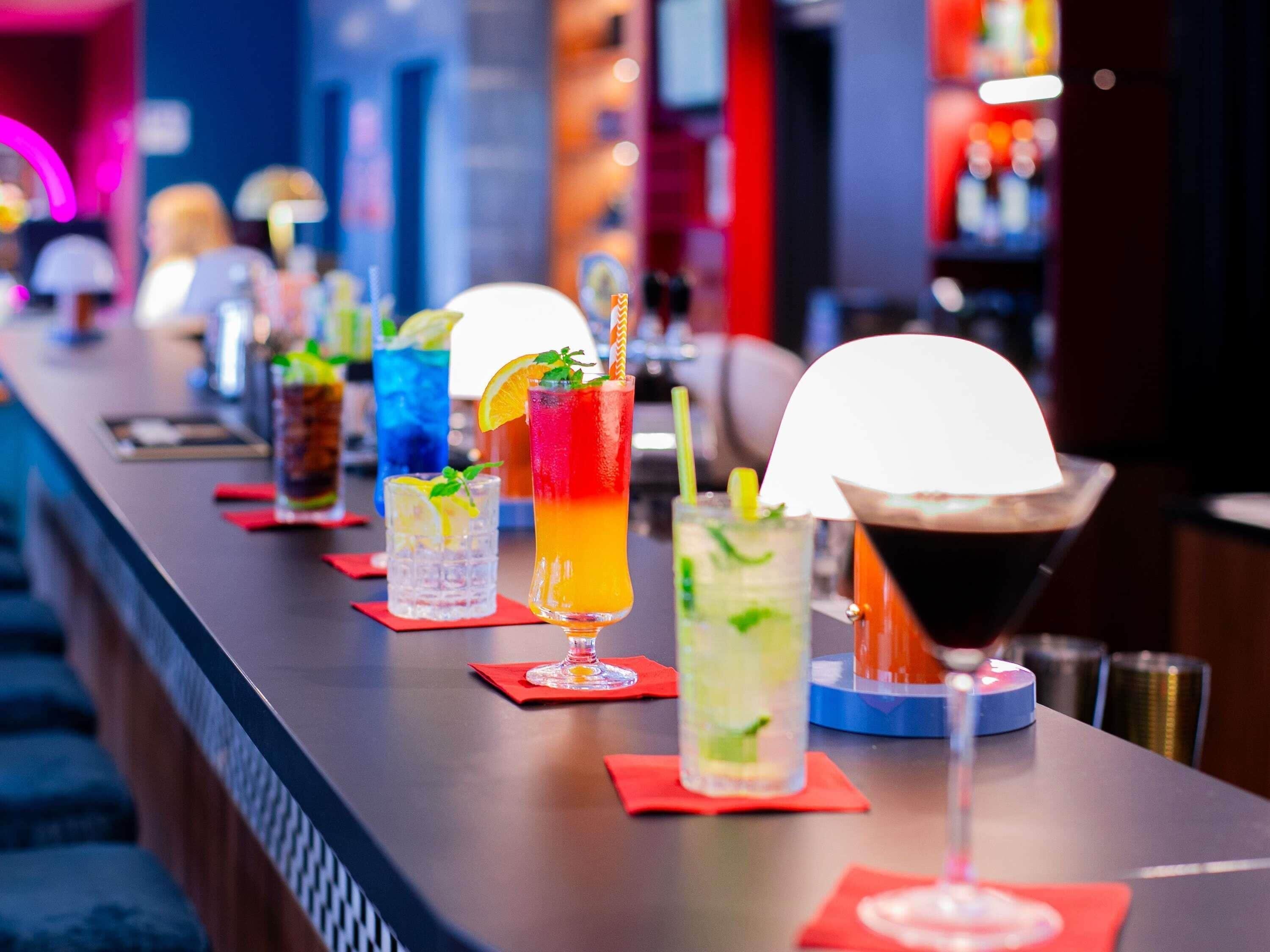 Un bar con diversas bebidas coloridas sobre la barra.