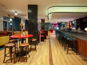 Eine moderne Bar mit Holzboden, Barhocker und einer Theke.