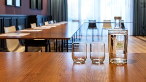 A conference room with a wooden table, two glasses, and a bottle of 'ibis Styles' on the table. - ibis Styles Walbrzych (Walbrzych)