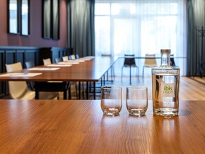 A conference room with a wooden table, two glasses, and a bottle of 'ibis Styles' on the table. - ibis Styles Walbrzych (Walbrzych)