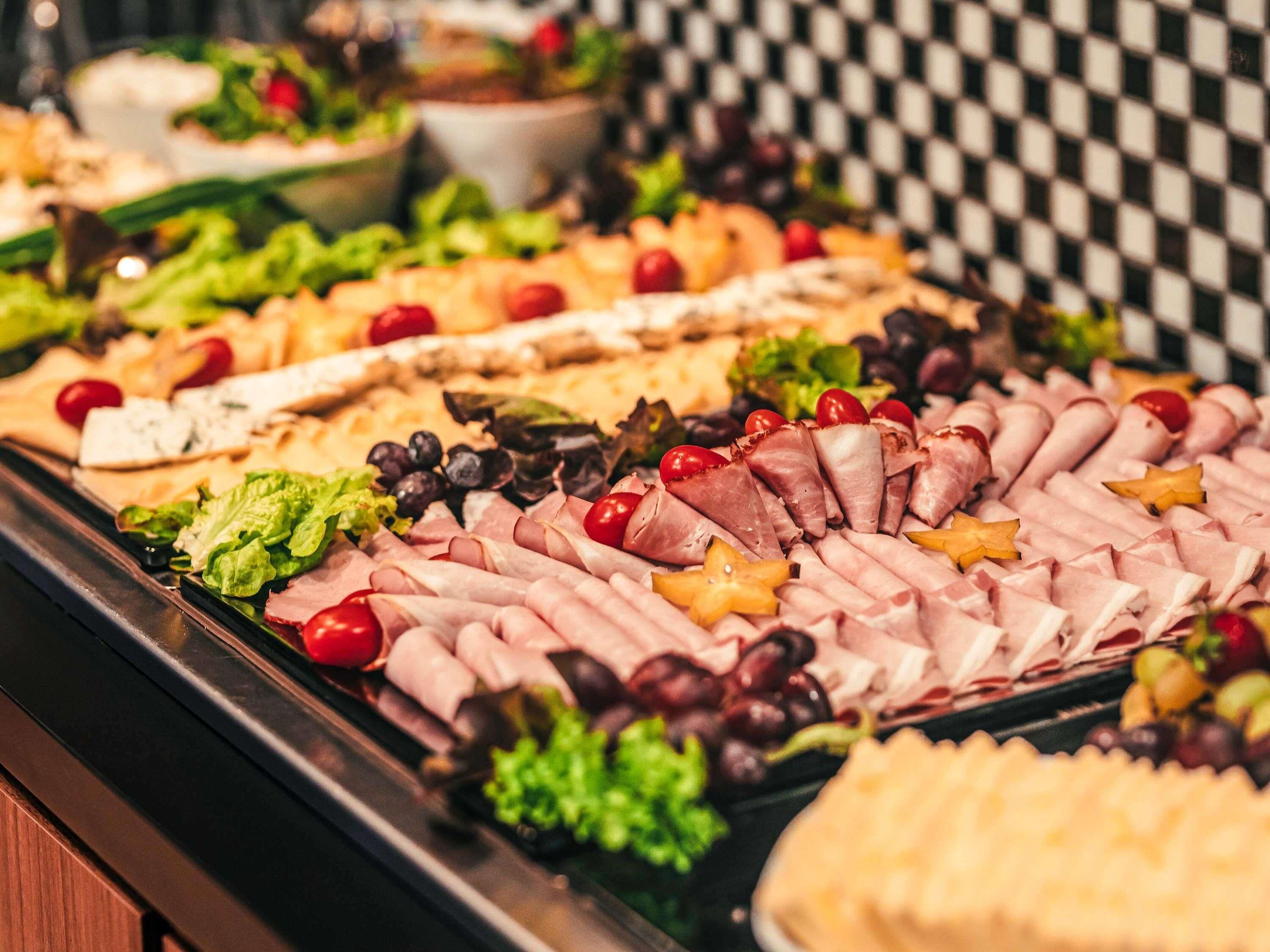 A buffet with various food items including meats, cheeses, and fruits.