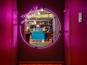 A neon sign with the text 'Travel is my therapy' and a reception desk in the background. - ibis Styles Walbrzych (Walbrzych)