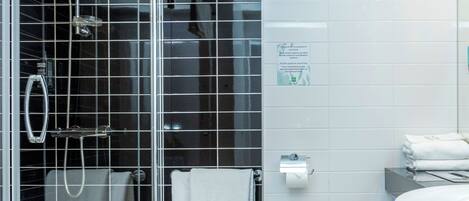 Un baño moderno con ducha envuelta en vidrio, inodoro blanco y lavamanos.