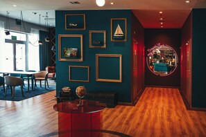 A modern hotel lobby with a wooden floor, a reception desk, and a seating area with tables and chairs. - ibis Styles Walbrzych (Walbrzych)