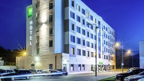Un hotel moderno con un llamativo letrero 'HOTEL', varios pisos y un estacionamiento con coches.
