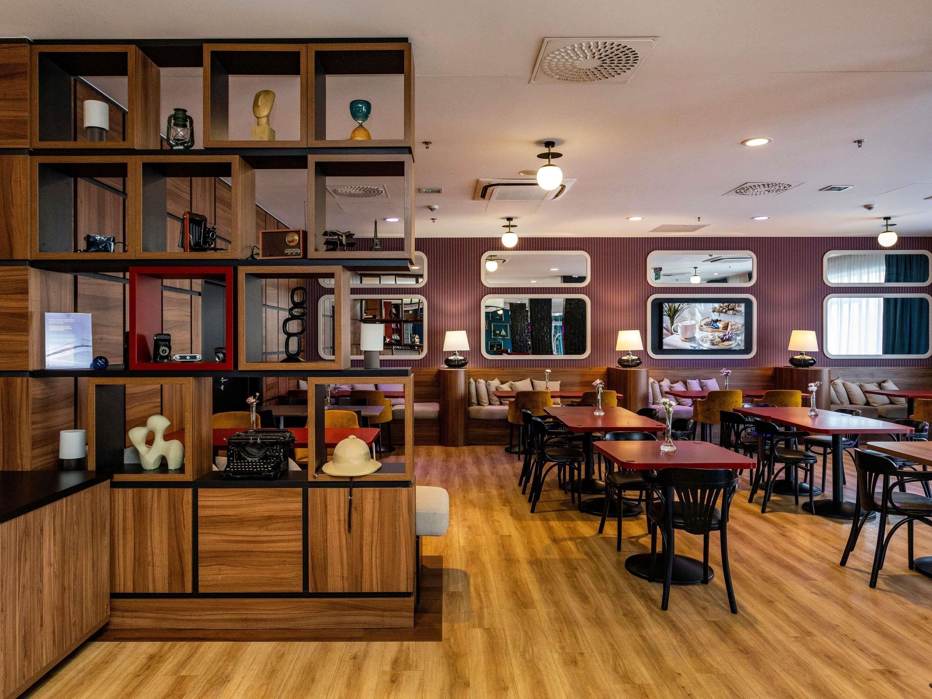 A restaurant with wooden furniture, multiple seating areas, and a variety of decorative items on shelves.