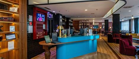 A hotel lobby with a reception desk, seating area, and a bar.