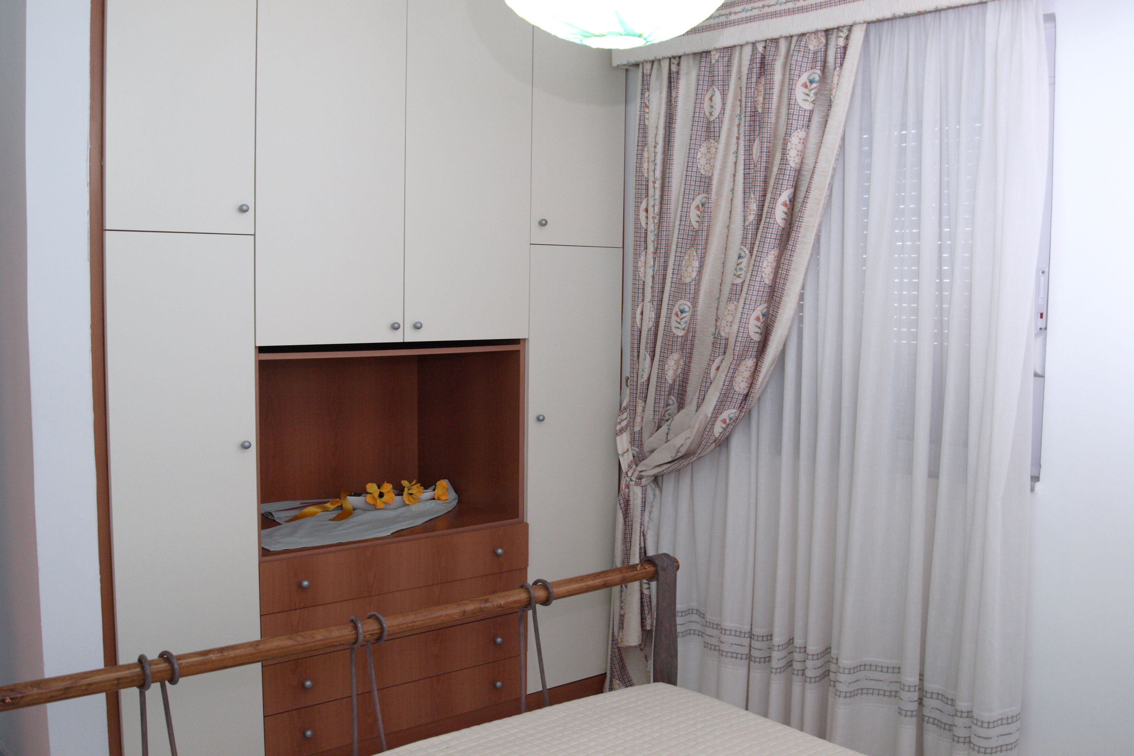 A bedroom with a bed, a wardrobe, and a window with curtains.