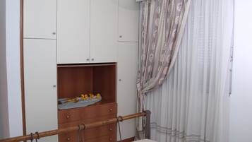 A bedroom with a bed, a wardrobe, and a window with curtains.