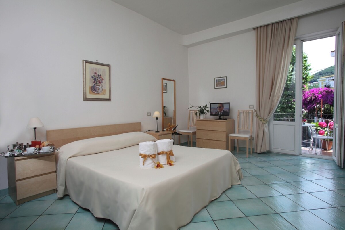 Une chambre d’hôtel avec un lit, une table de chevet, une lampe et une vue sur l’extérieur.