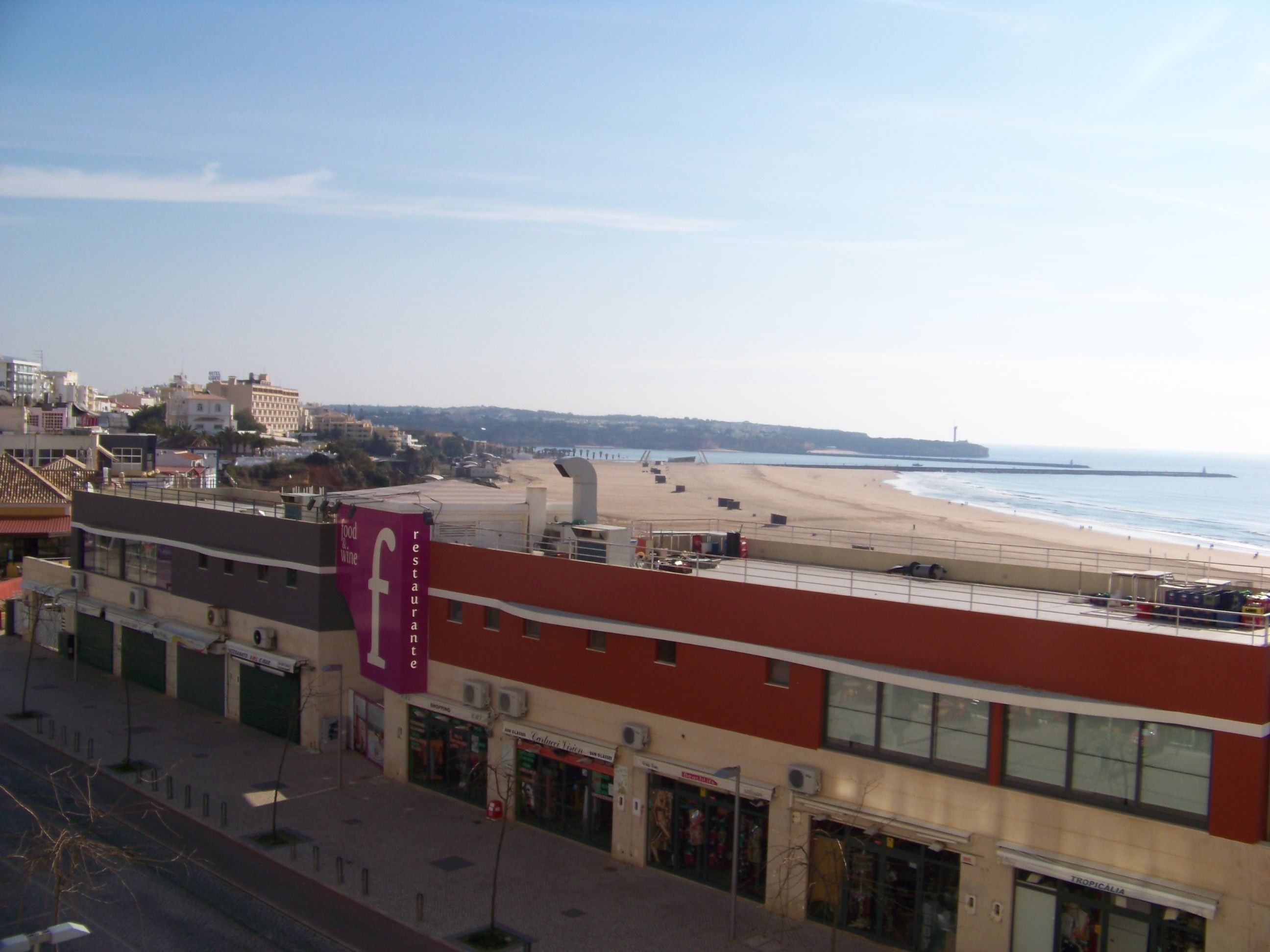 A coastal cityscape with a beach, buildings, and a clear sky.