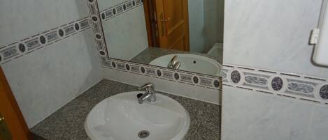 A bathroom with a white sink, granite countertop, and a mirror with decorative tiles.