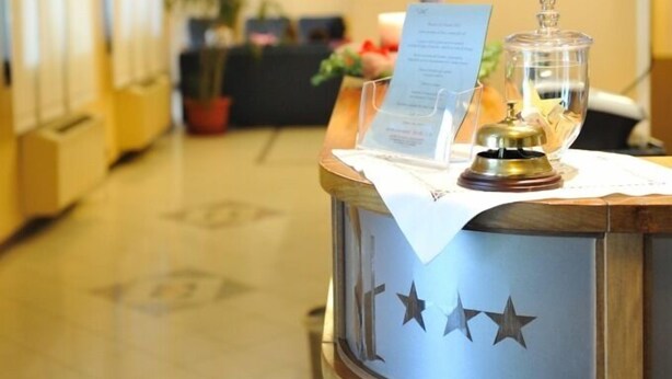 A reception desk with a menu, a decorative glass container, and a framed picture on the wall. - Hotel Rometta (Cittadella)