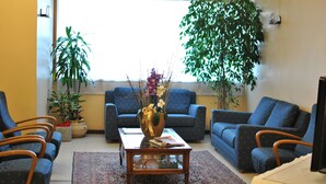 A living room with a sofa set, a coffee table, and two potted plants. - Hotel Rometta (Cittadella)