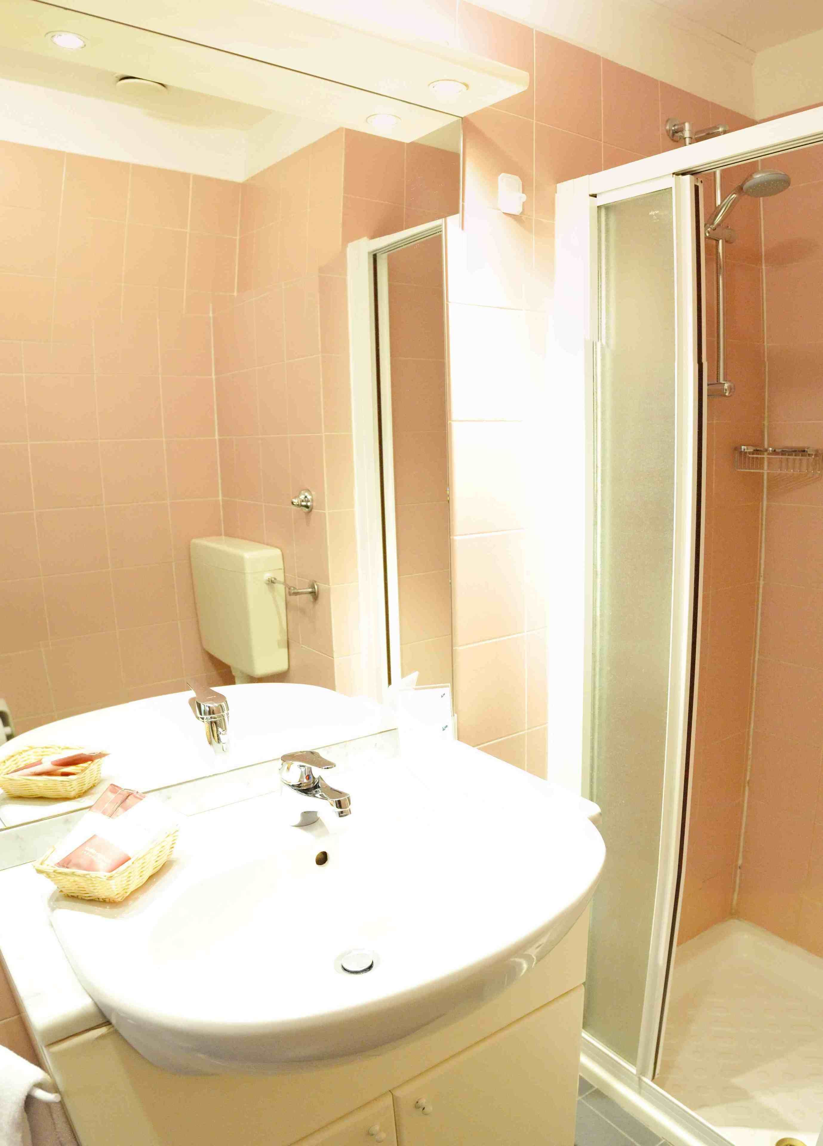 Un bagno con lavandino, specchio e doccia.