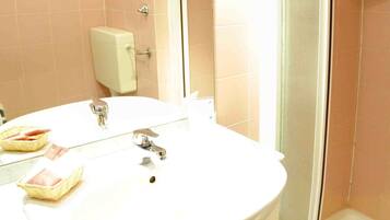Un bagno con lavandino, specchio e doccia.