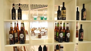 A wine rack with bottles labeled '32' and a dining area with chairs and a table. - Hotel Rometta (Cittadella)