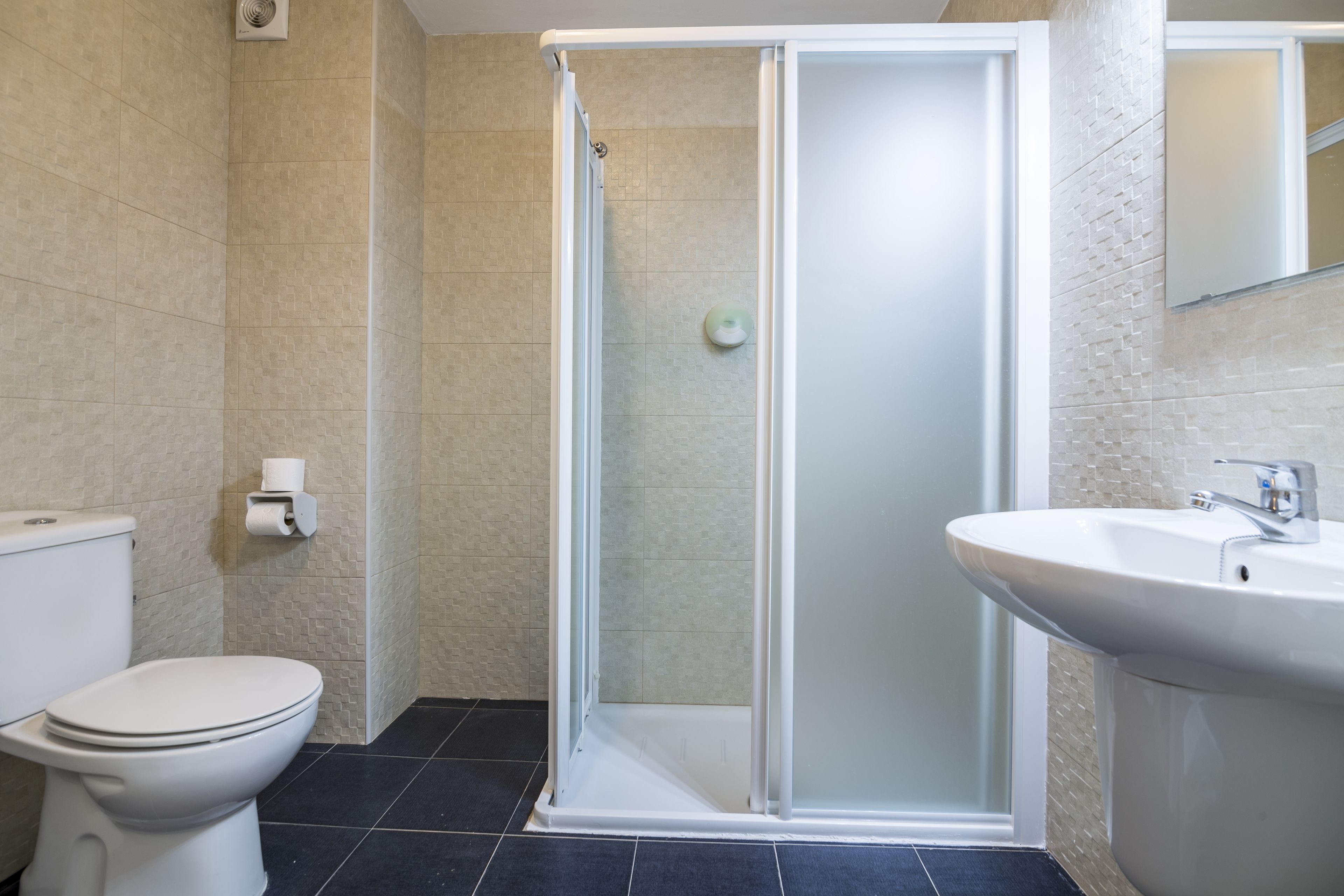 A bathroom with a toilet, a shower with a glass door, and a sink.