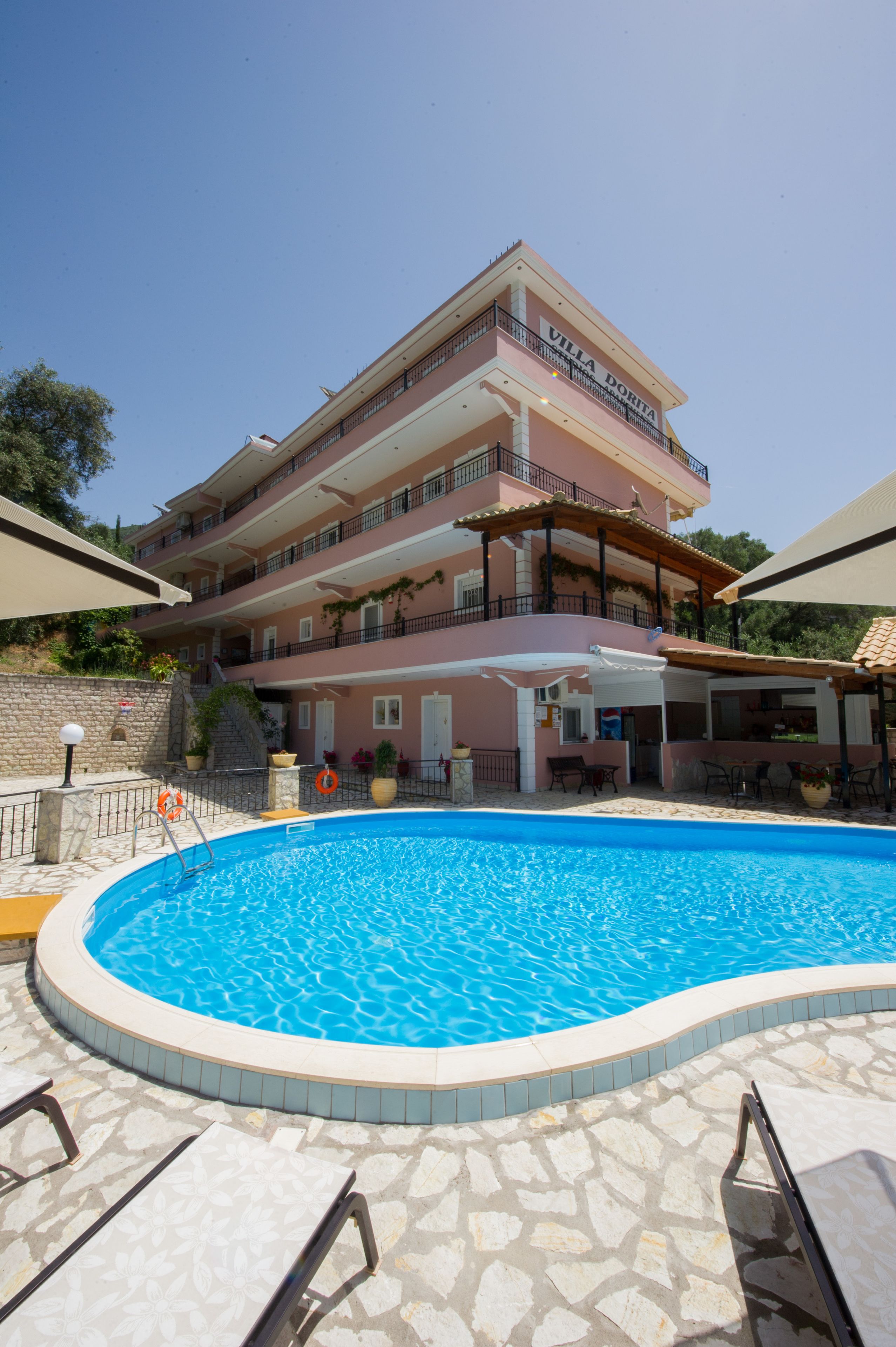 A multi-story hotel with a swimming pool, outdoor seating, and a covered patio area.