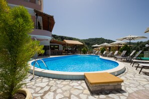 Una piscina al aire libre, sombrillas, sillones reclinables de piscina