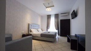 Ein modernes Hotelzimmer mit einem großen Bett, einem Schreibtisch und einem Fernseher.