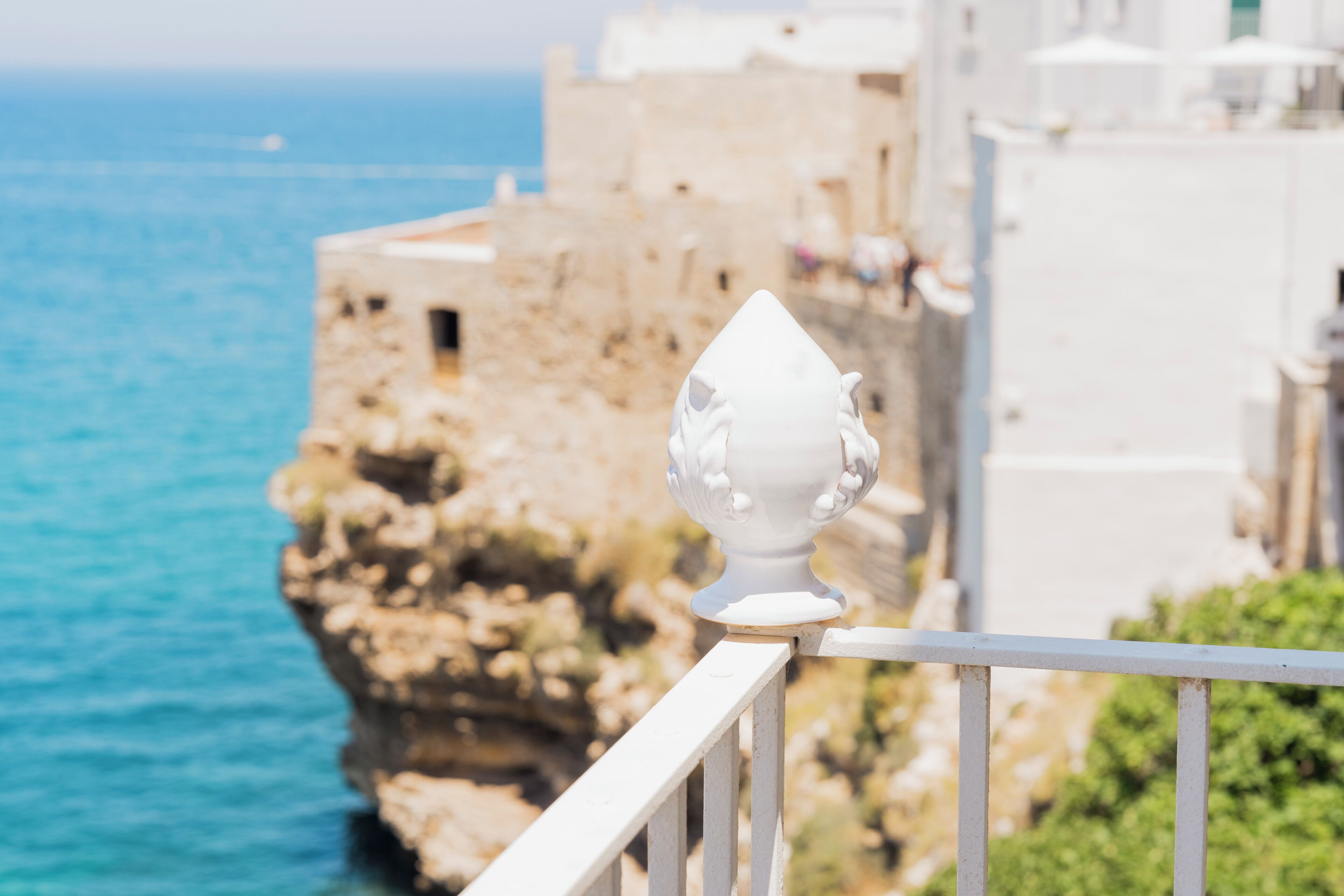 A coastal building with a balcony railing and a view of the sea.