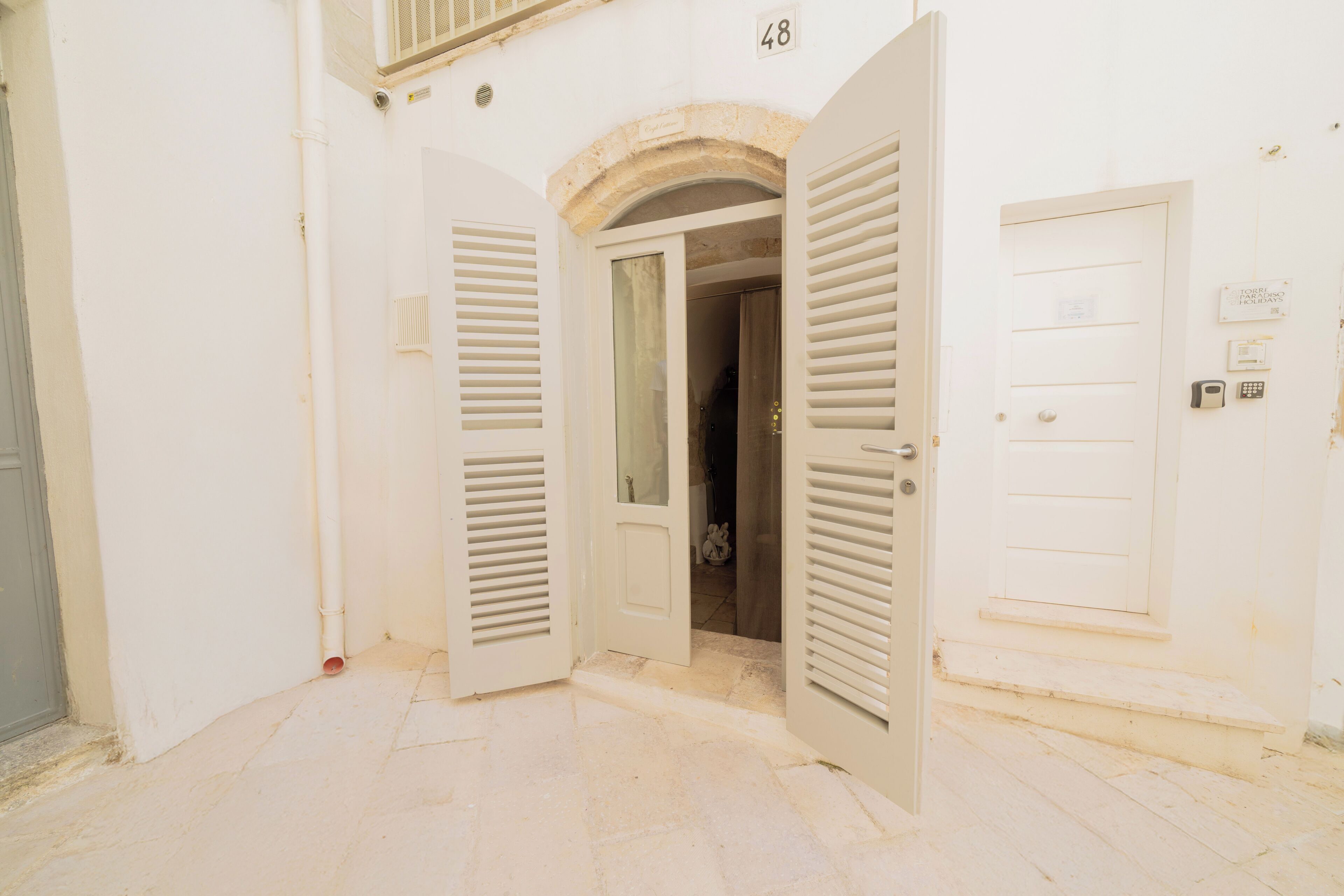An open door leading to a room with a tiled floor and a stone archway above.