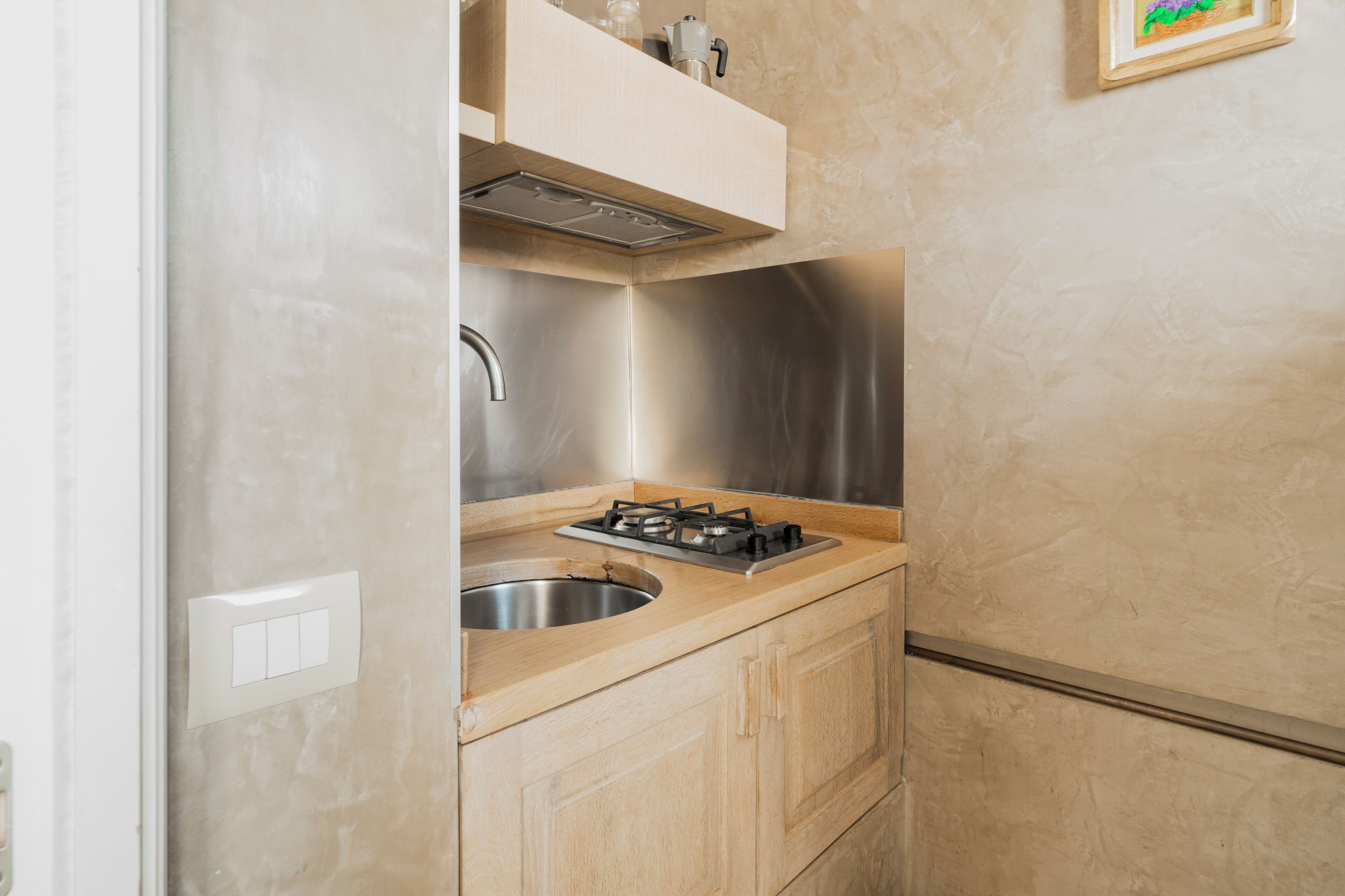 A compact kitchen with a stainless steel sink, a gas stove, and wooden cabinets.