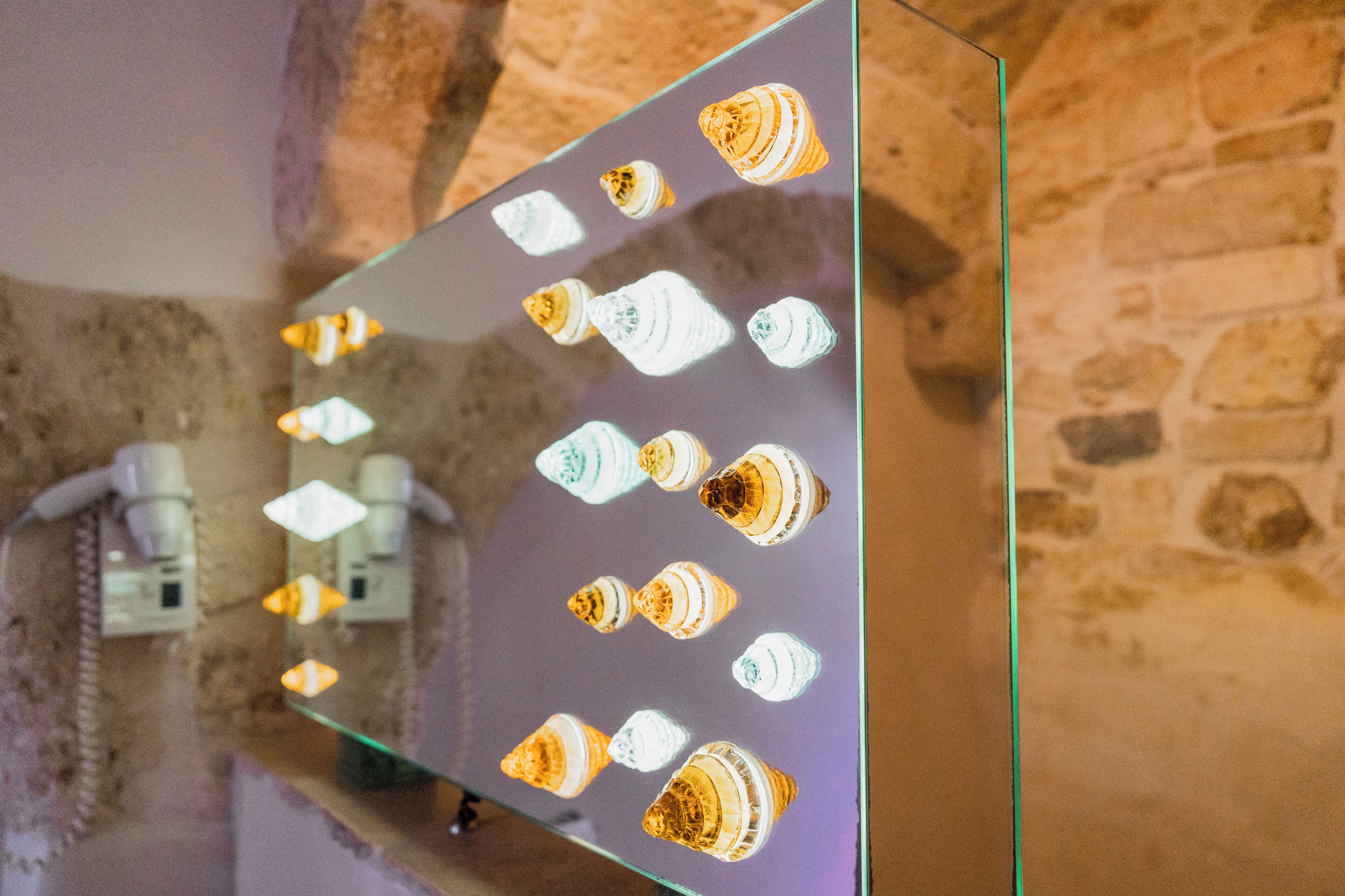 A mirrored wall with multiple bottles and a stone wall background.