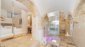 Un baño moderno con un arco de piedra, cabina de ducha de vidrio y bañera blanca.