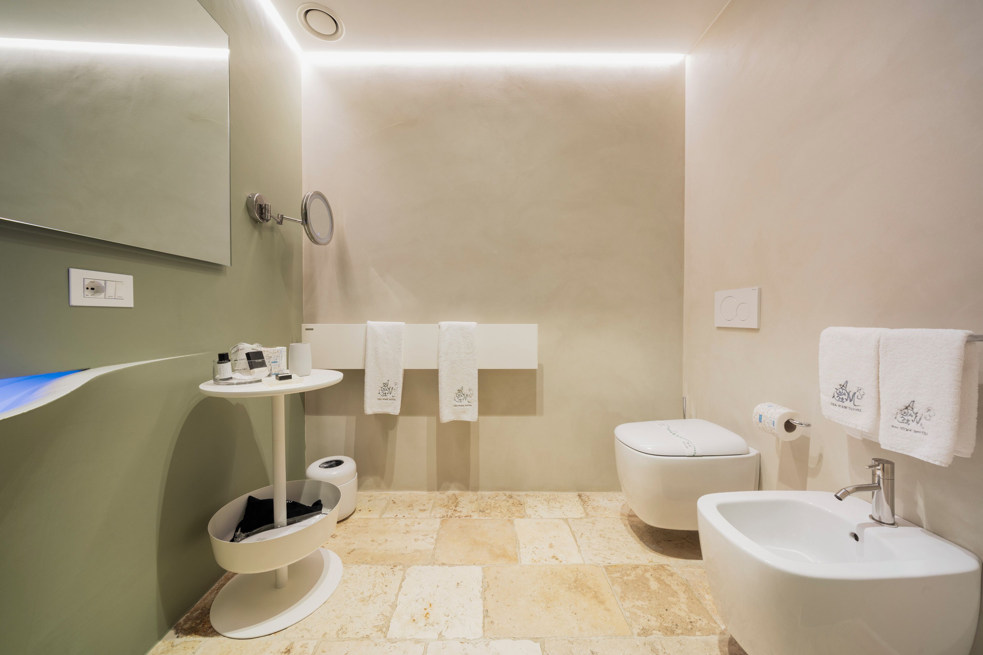 A bathroom with a toilet, bidet, sink, and a mirror.