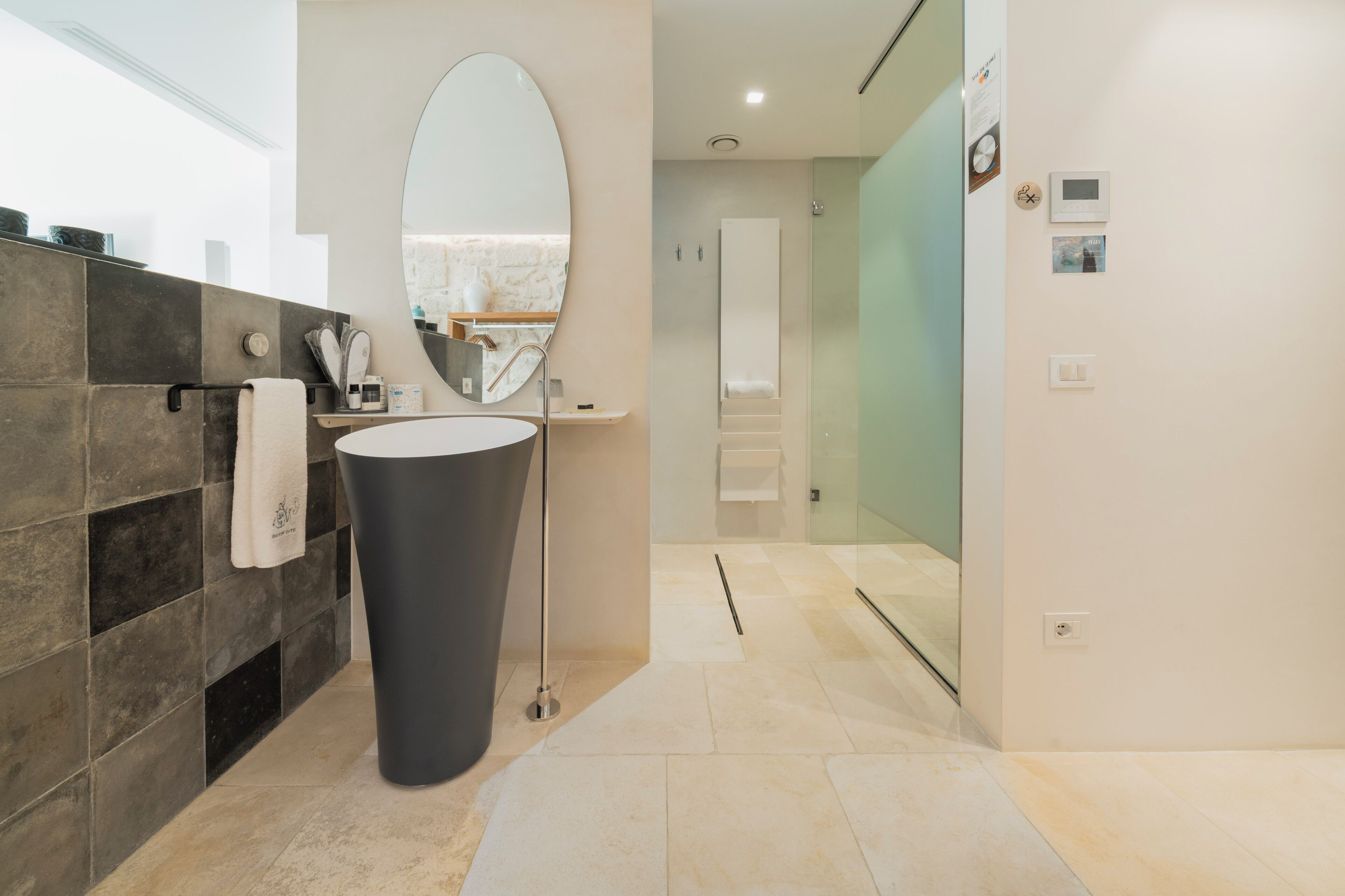 A modern bathroom with a large sink, a mirror, a towel rack, and a glass shower enclosure.