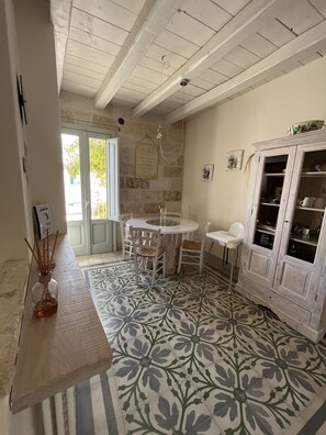 A kitchen with a round table, chairs, a cabinet, and a patterned floor. - Antico Mondo Rooms & Suites (Polignano a Mare)