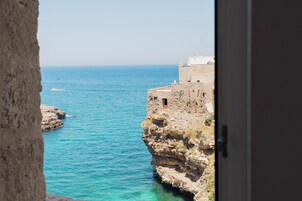 Vista costera con un edificio de piedra que domina el mar.