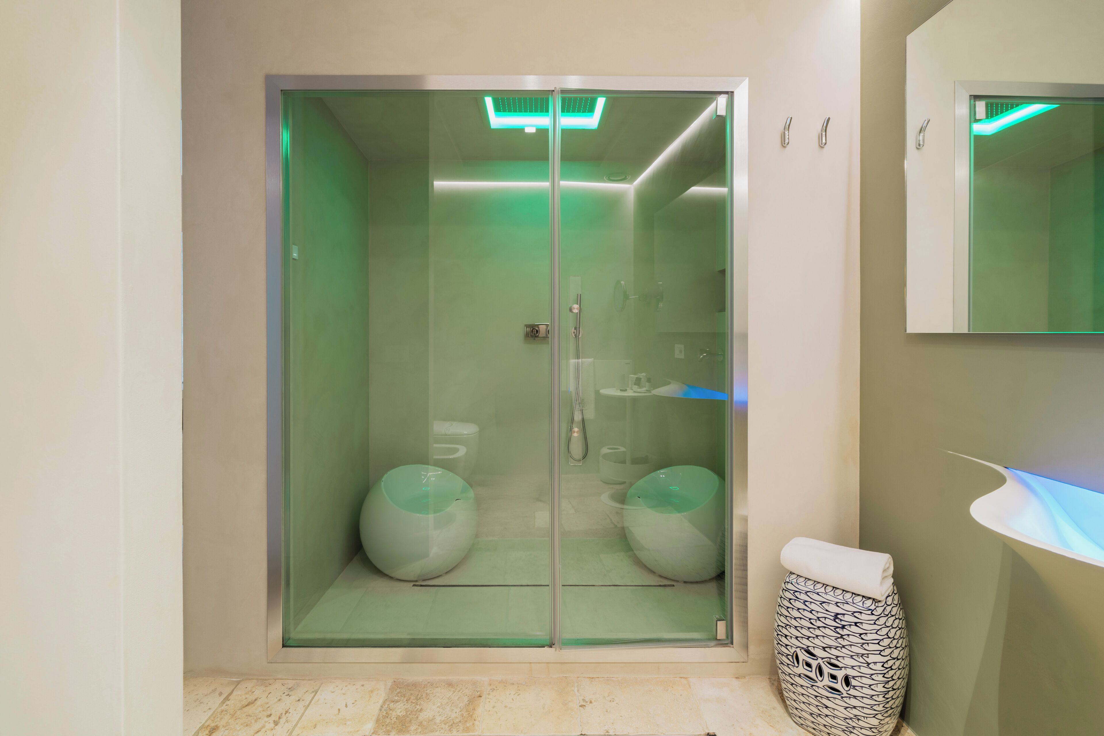 Un bagno moderno con doccia vetrata, lavandino con specchio e cestino con motivo decorativo.