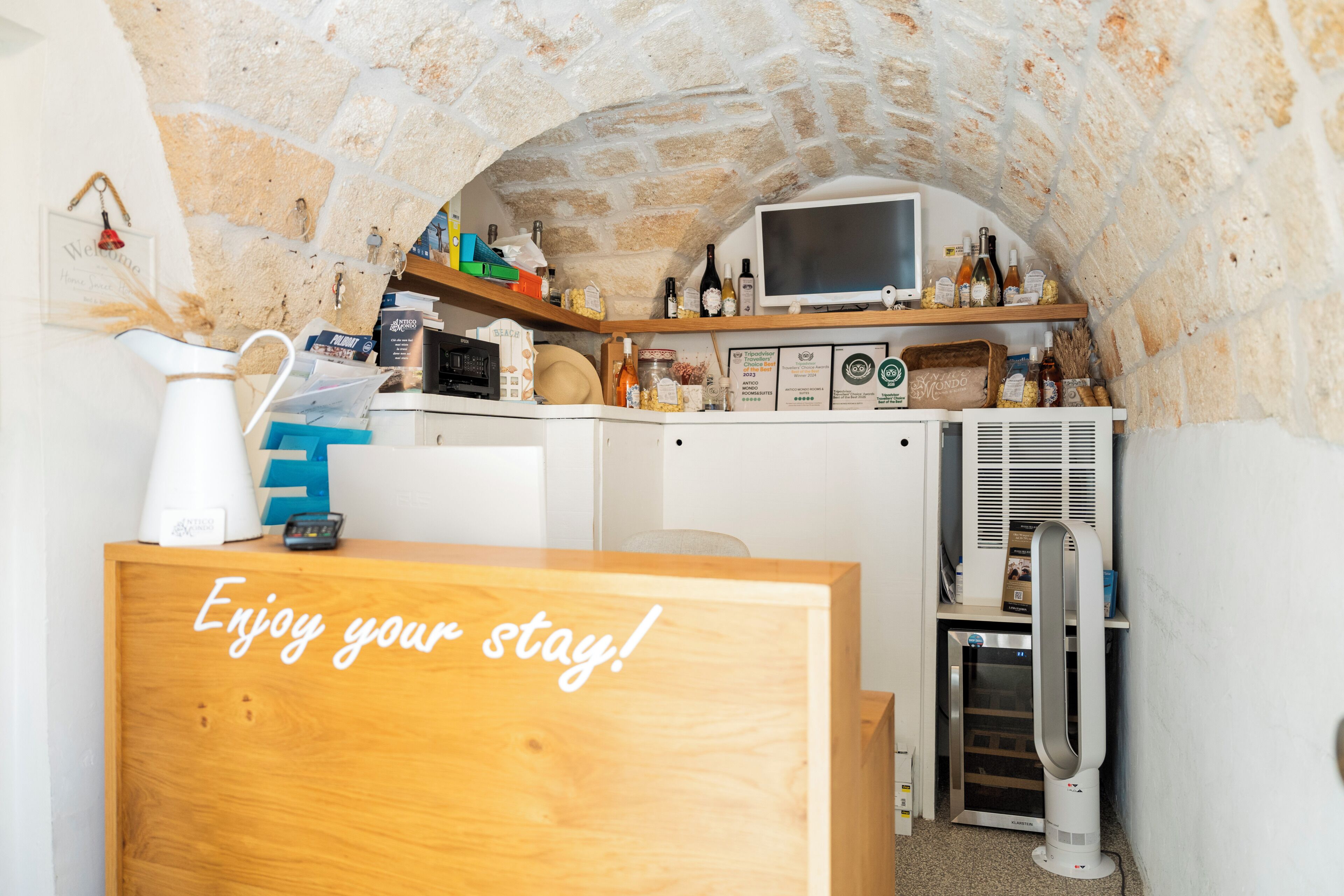 A cozy room with a stone arch, a wooden desk, a television, and various amenities.