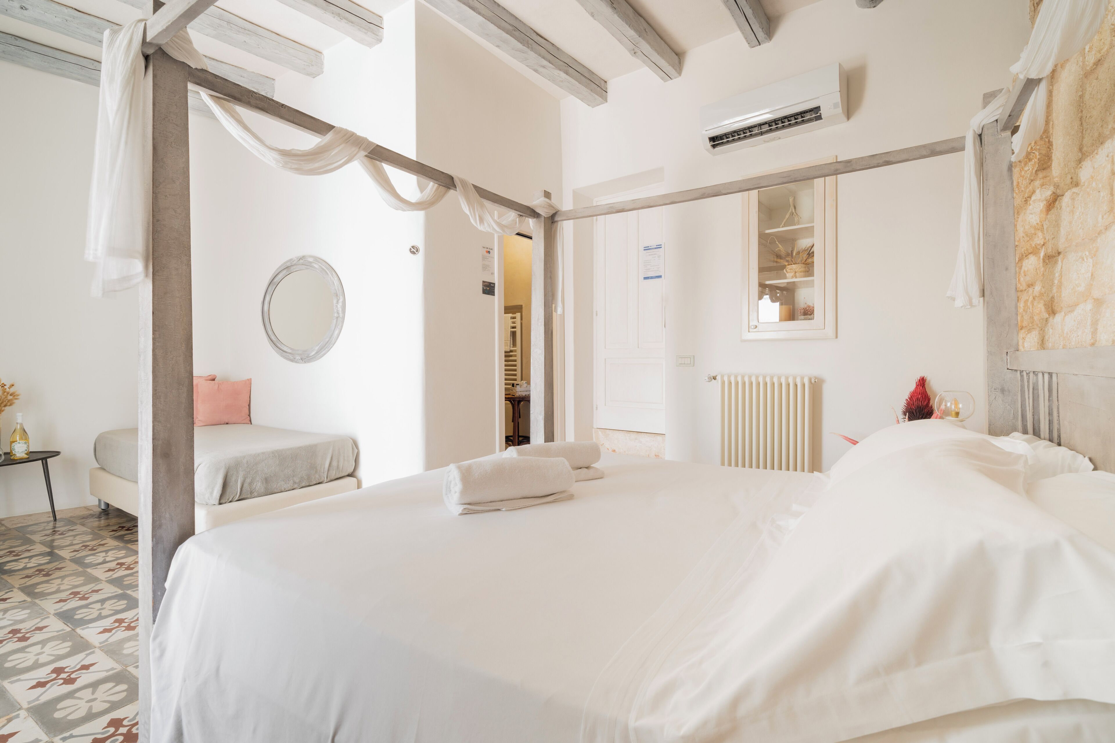 A bedroom with a large bed, a bedside table, a mirror, and a radiator.