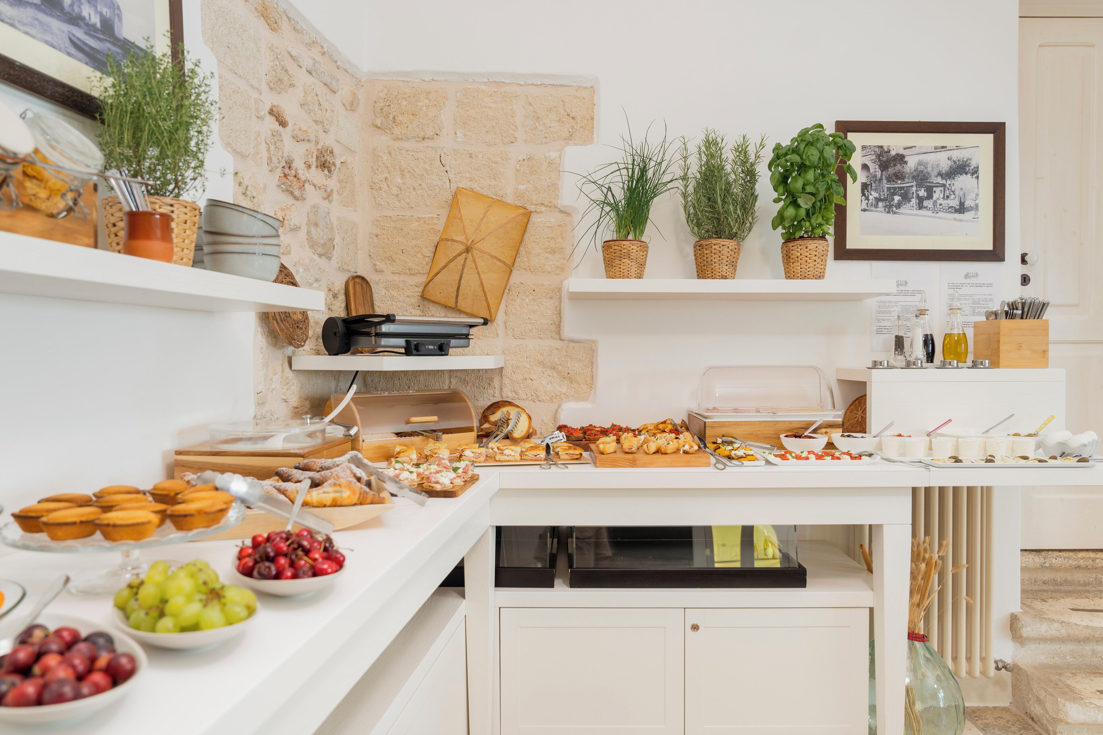 A buffet setup with various food items, a stone wall, and potted plants.