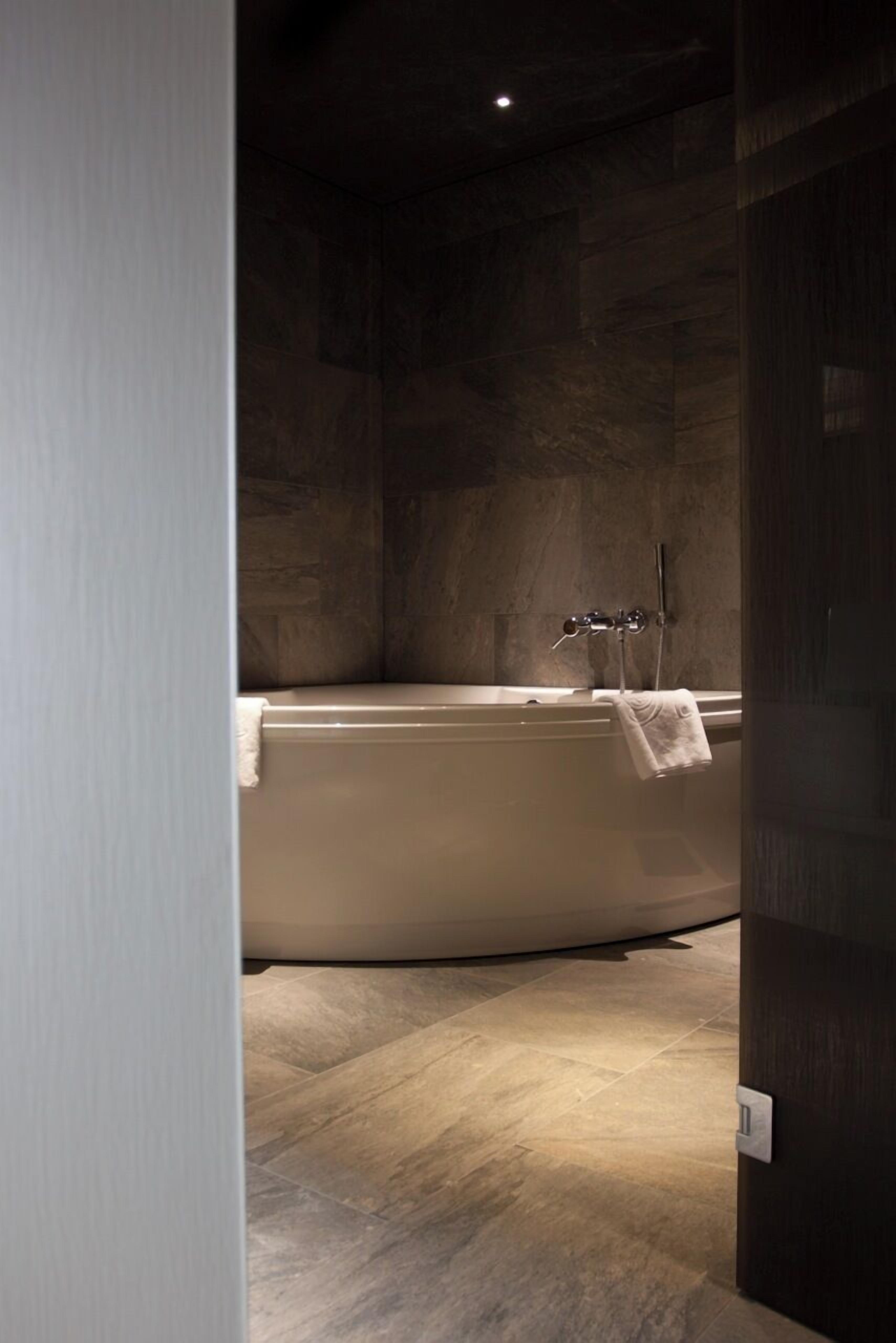 A modern bathroom with a freestanding bathtub, a towel rack, and a visible light switch on the wall.