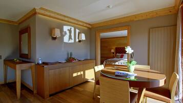 Une chambre d’hôtel avec un bureau en bois, un lit doté d’une tête de lit, une table à manger avec des chaises et un grand miroir au mur.