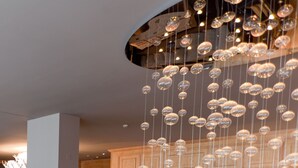 Un interior moderno con una escalera de cristal, detalles de madera y una lámpara colgante.