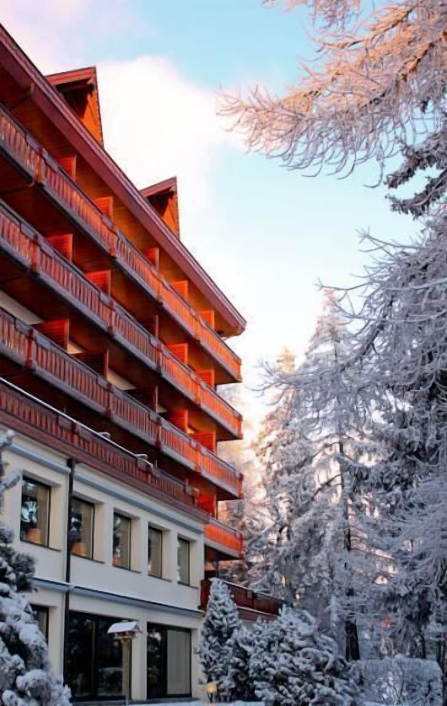 Un hotel de varios pisos con balcones y un paisaje nevado.