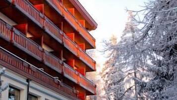 Un hotel de varios pisos con balcones y un paisaje nevado.