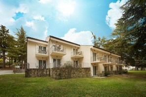A multi-story building with balconies, stone foundation, and a grassy lawn. - Villas with Balcony or Terrace - Hotel & Resort Adria Ankaran (Ankaran)