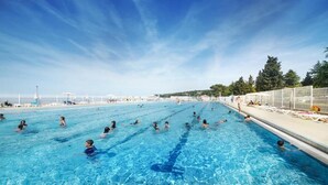 A large outdoor swimming pool with multiple lanes, surrounded by a fence and trees. - Villas with Balcony or Terrace - Hotel & Resort Adria Ankaran (Ankaran)
